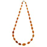 A NECKLACE OF 28 GRADUATED AMBER BEADS WITH COLOURED GLASS SPACERS, APPROXIMATELY 60CM L, 40G Some