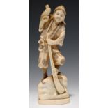 A JAPANESE IVORY OKIMONO OF A HUNTER HOLDING A GUN IN HIS LEFT HAND AND A BIRD IN HIS RIGHT, 15CM H,