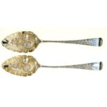 A PAIR OF GEORGE III SILVER TABLE SPOONS, LATER CHASED AND GILT AS BERRY SPOONS, ONE ENGRAVED WITH