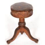 A VICTORIAN WALNUT PIANO STOOL, THE TURNED PILLAR AND THREE SCROLLING LEGS CRISPLY CARVED WITH IVY