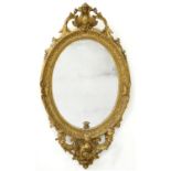 A VICTORIAN OVAL GILTWOOD AND COMPOSITION GIRANDOLE, WITH LEAFY SCROLLING CABOCHON CRESTING AND