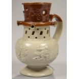 AN ENGLISH SALTGLAZED BROWN STONEWARE PUZZLE JUG, SPRIGGED WITH TOPER, WINDMILL AND OTHER