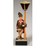 A POLYCHROMED WOOD WHISTLING TRAMP AUTOMATON, STANDING BESIDE A LAMP POST WITH METAL LANTERN, 47CM