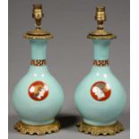 A PAIR OF FRENCH GILT BRASS MOUNTED PORCELAIN OIL LAMPS, THE BOTTLE SHAPED VASE PRINTED AND