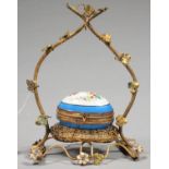 A PALAIS ROYALE GILTMETAL RUSTIC WATCH STAND SET WITH AN OVAL PORCELAIN TRINKET BOX OIN THE FORM