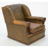 A BRASS NAILED HIDE ARMCHAIR WITH WING BACK, THE BROAD PADDED ARMS WITH OAK FACINGS, SEAT HEIGHT
