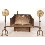 A CAST IRON FIREGRATE, THE TRIPOD ANDIRONS IN 17TH C STYLE WITH PIERCED AND ENGRAVED BRASS DISC