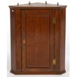 A SPLAY FRONTED OAK HANGING CORNER CUPBOARD WITH RAISED AND FIELDED PANEL TO THE DOOR, BRASS 'H'