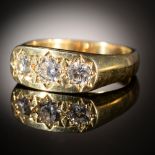 A DIAMOND RING gipsy set with three modified round brilliant cut diamonds, in 18ct gold, London