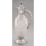 A VICTORIAN SILVER MOUNTED CUT GLASS CLARET JUG on silver foot, engraved within a cartouche
