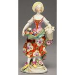 A DERBY FIGURE OF A LADY ATTIRED AS A SHEPHERDESS, C1760  gathering fruit and flowers in her