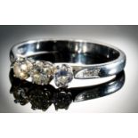 A DIAMOND THREE STONE RING with round brilliant cut diamonds and diamond set shoulders, in 18ct