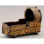 A SLIPWARE MODEL OF A CRADLE, STAFFORDSHIRE OR YORKSHIRE, DATED 1823 of coarse red fabric, painted
