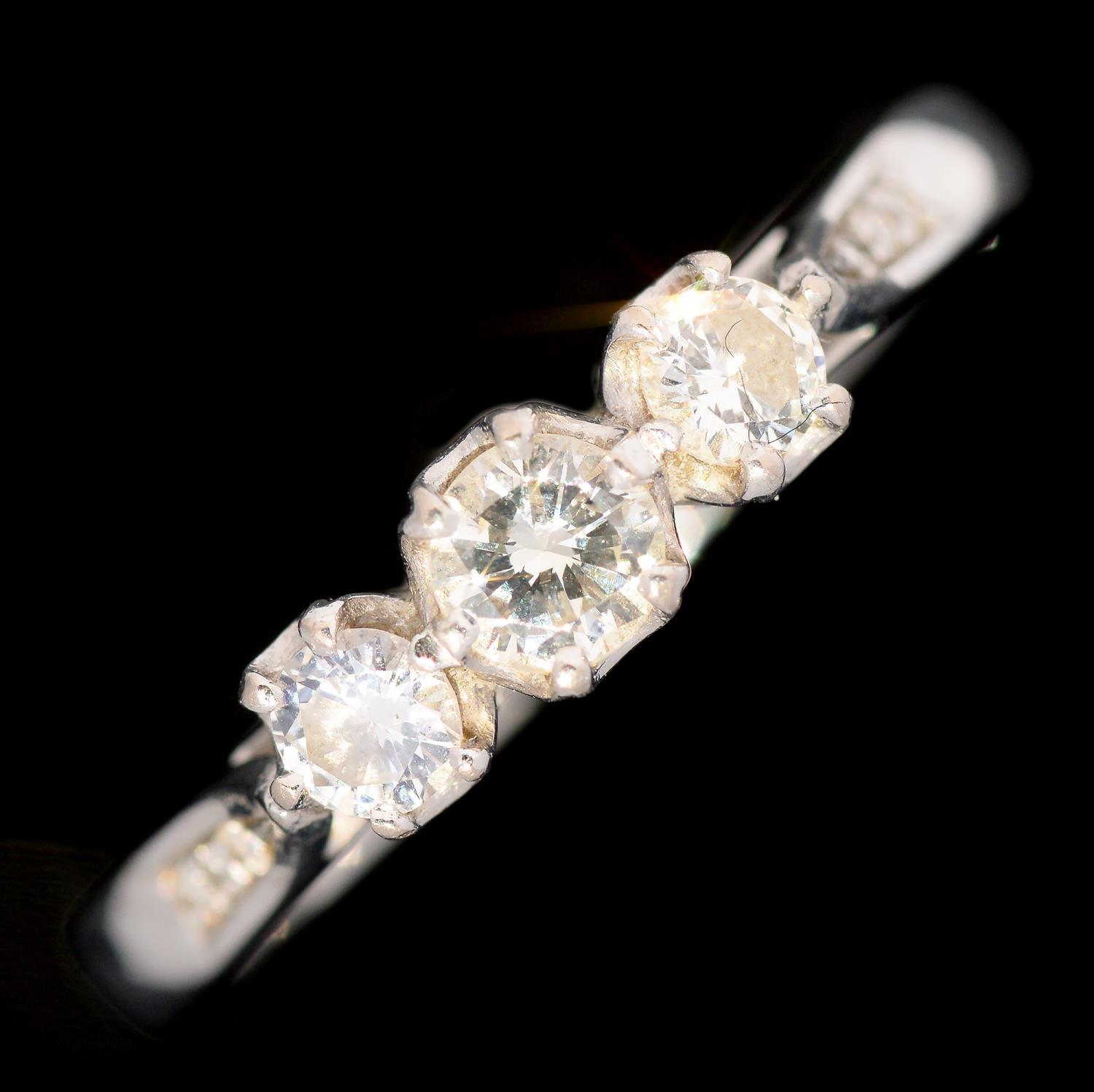 A DIAMOND THREE STONE RING with round brilliant cut diamonds and diamond set shoulders, in 18ct - Image 2 of 7