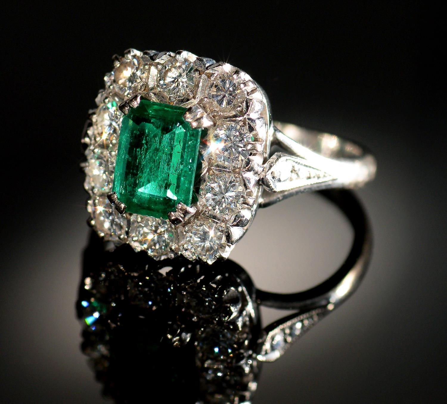 AN EMERALD AND DIAMOND RING  the step cut emerald of approx 4 x 6mm in a surround of ten evenly