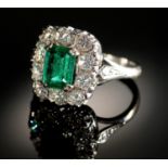 AN EMERALD AND DIAMOND RING  the step cut emerald of approx 4 x 6mm in a surround of ten evenly