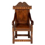 AN OAK AND INLAID PANEL BACK CHILD'S ARMCHAIR in 17th century English style, the cresting carved