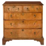 A WALNUT AND FEATHERBANDED CHEST OF DRAWERS,with quarter veneered top and brass drop handles, on