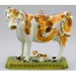 A PRATTWARE COW CREAMER AND CALF, C1800  with ochre sponged decoration, the crisply moulded base