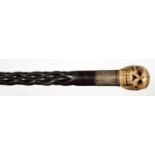 A SPIRALLY CARVED EBONY WALKING CANE WITH CARVED BONE HUMAN SKULL POMMEL AND SILVERED METAL MOUNT,