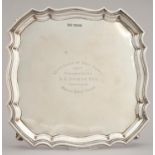 GOLFING INTEREST. A GEORGE V SHAPED SQUARE SILVER SALVER WITH MOULDED BORDER, ON FOUR FEET, ENGRAVED