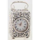 AN EDWARD VII MINIATURE SILVER CARRIAGE TIMEPIECE, THE BALE SHAPED CASE CRISPLY EMBOSSED WITH