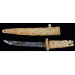 A JAPANESE IVORY DAGGER AND SHEATH, THE HILT CARVED AS THE HEAD OF A MONSTER, THE SHEATH WITH A