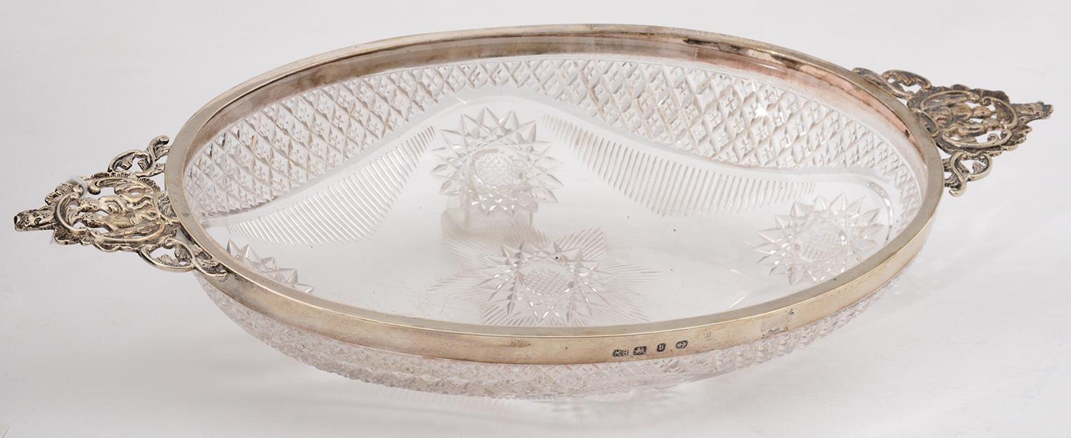 A VICTORIAN OVAL SILVER MOUNTED CUT GLASS BOWL, WITH CAST OPENWORK CHERUBS AND MASK HANDLES, 29CM