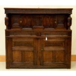 AN OAK LIVERY CUPBOARD, EARLY 18TH C, CARVED WITH STYLISED FOLIAGE AND STRAPWORK, THE UPPER PART