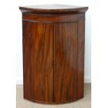 A GEORGE III BOW FRONTED MAHOGANY HANGING CORNER CUPBOARD, EARLY 19TH C,  WITH FLARED CORNICE AND