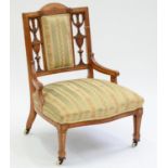 A VICTORIAN CARVED AND INLAID SATINWOOD NURSING CHAIR, C1890, THE SLIGHTLY CURVED BACK CRESTED BY