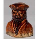 A VICTORIAN TREACLE BROWN GLAZED EARTHENWARE BANK AS THE BUST OF A SMILING MAN, C1840, THE DIPPED