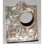 AN EDWARDIAN SILVER CLOCK FRAME, EMBOSSED WITH A DOZING MAN AND BULLDOG ABOVE INSCRIPTION "WAKE UP",