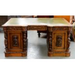 A VICTORIAN CARVED AND PANELLED OAK BREAKFRONT PEDESTAL DESK WITH GREEN TOOLED LEATHER INLET TOP,