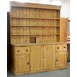 A VICTORIAN WAXED PINE DRESSER WITH BOARDED RACK, THE LOWER PART ENCLOSED BY PANELLED DOORS, 238CM