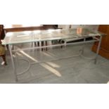 A GLASS TOPPED DINING TABLE ON TUBULAR STEEL STRETCHER BASE, 75CM H; 183 X 63CM
