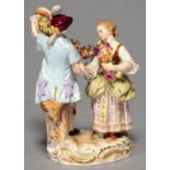 A MEISSEN GROUP OF DANCERS WITH A GARLAND, 20TH C, THE YOUTH IN A PLUMED HAT BEFORE A STUMP, ON OVAL