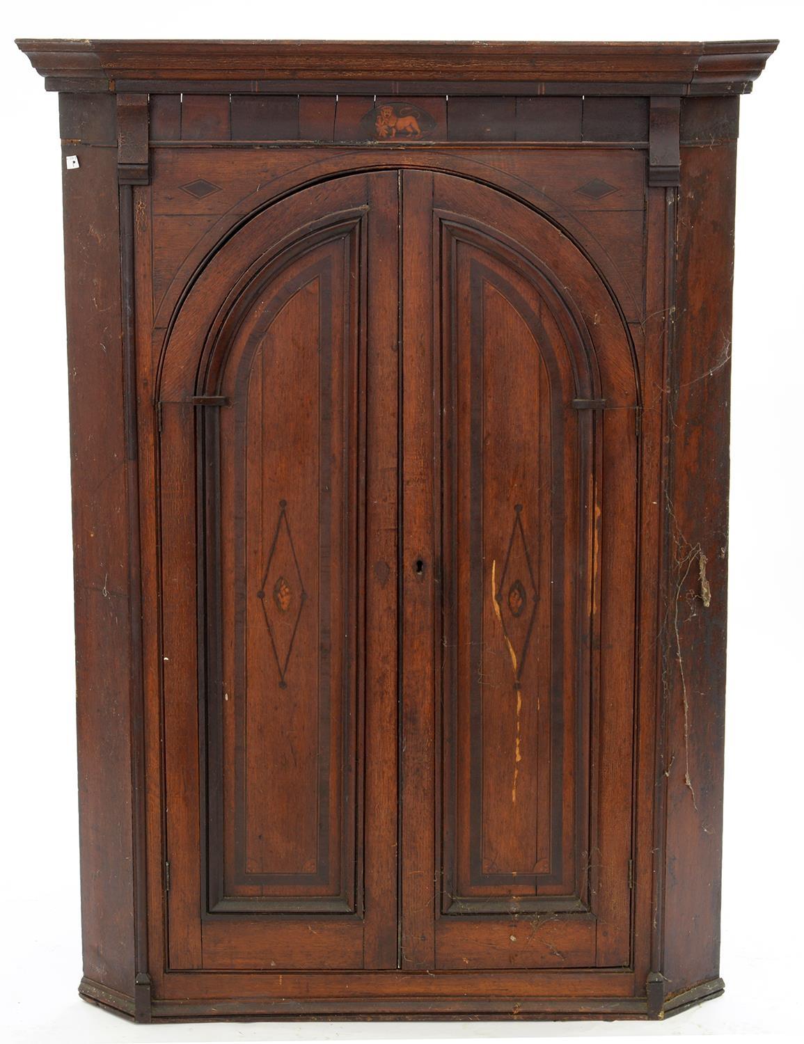A GEORGE III INLAID OAK CORNER CUPBOARD WITH ARCH PANELLED DOORS WITH LION PATERAE, 135CM H; 101 X