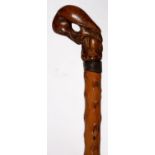 A GNARLED WOOD WALKING CANE, LATE 19TH C, WITH A CARVED WOOD POMMEL IN THE FORM OF A BIRD PECKING