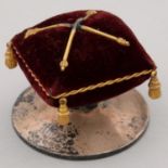 NEEDLEWORK TOOLS. A GEORGE V COMMEMORATIVE SILVER MAROON VELVET AND GILT TASSELED PIN CUSHION,