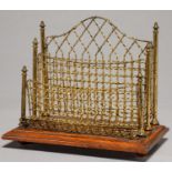 A LACQUERED BRASS AND WIRE MESH LETTER RACK BY MARION & CO, C1890, ON OAK BASE AND BRASS BALL