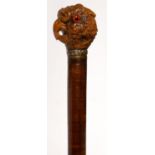 A VARNISHED TIGHTLY COILED LEATHER AND HARDWOOD WALKING CANE, LATE 19TH C WITH A CRISPLY CARVED