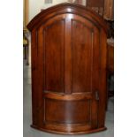 A MAHOGANY STAINED BOW FRONTED HANGING CORNER CUPBOARD, 19TH C, WITH LANCET ARCHED CORNICE AND