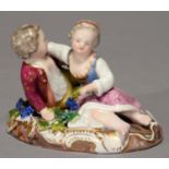 A GERMAN PORCELAIN GROUP OF CHILDREN, 20TH C, RECLINING ON AN OVAL GILT BASE WITH BUNCHES OF GRAPES,