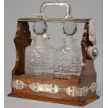 AN EDWARDIAN EPNS MOUNTED OAK TANTALUS, C1905, WITH PAIR OF CUT GLASS DECANTERS AND STOPPERS, 30CM H