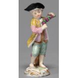 A MEISSEN FIGURE OF A GRAPE HARVESTER, C1870, THE BAREFOOT YOUTH IN STRIPED YELLOW AND GREEN COAT,