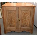 A PINE CUPBOARD, THE PANELS TO THE DOORS CARVED WITH LEAFY SCROLLS, 71CM H; 47 X 74CM Top with