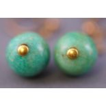 A yellow metal pair of drop earrings each having a circular polished green jade bead