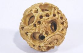 A carved wood devil's work ball with writhing dragon designs,