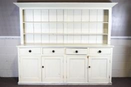 A white painted pine dresser, with four shallow drawers above two sets of twin cupboard doors,